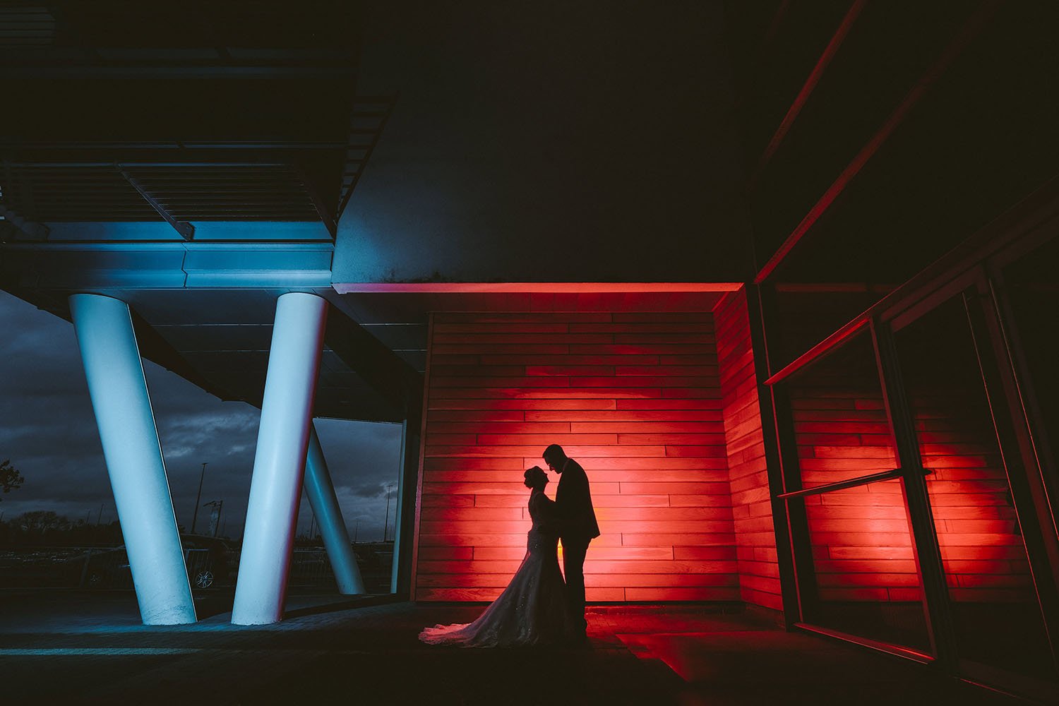 Newcastle wedding: bride and groom in silhouette against red and blue lighting at night