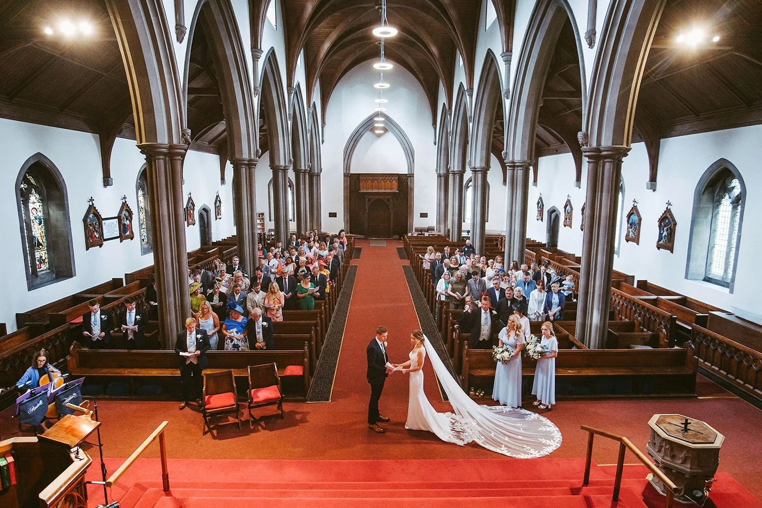 Ellingham Hall wedding: wedding ceremony seen from above in a gothic church with a red carpet aisle