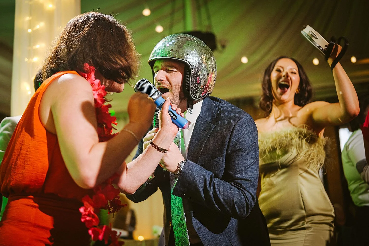 Beamish Hall wedding: guest in a mirrored disco helmet singing into a microphone beside a woman in an orange dress