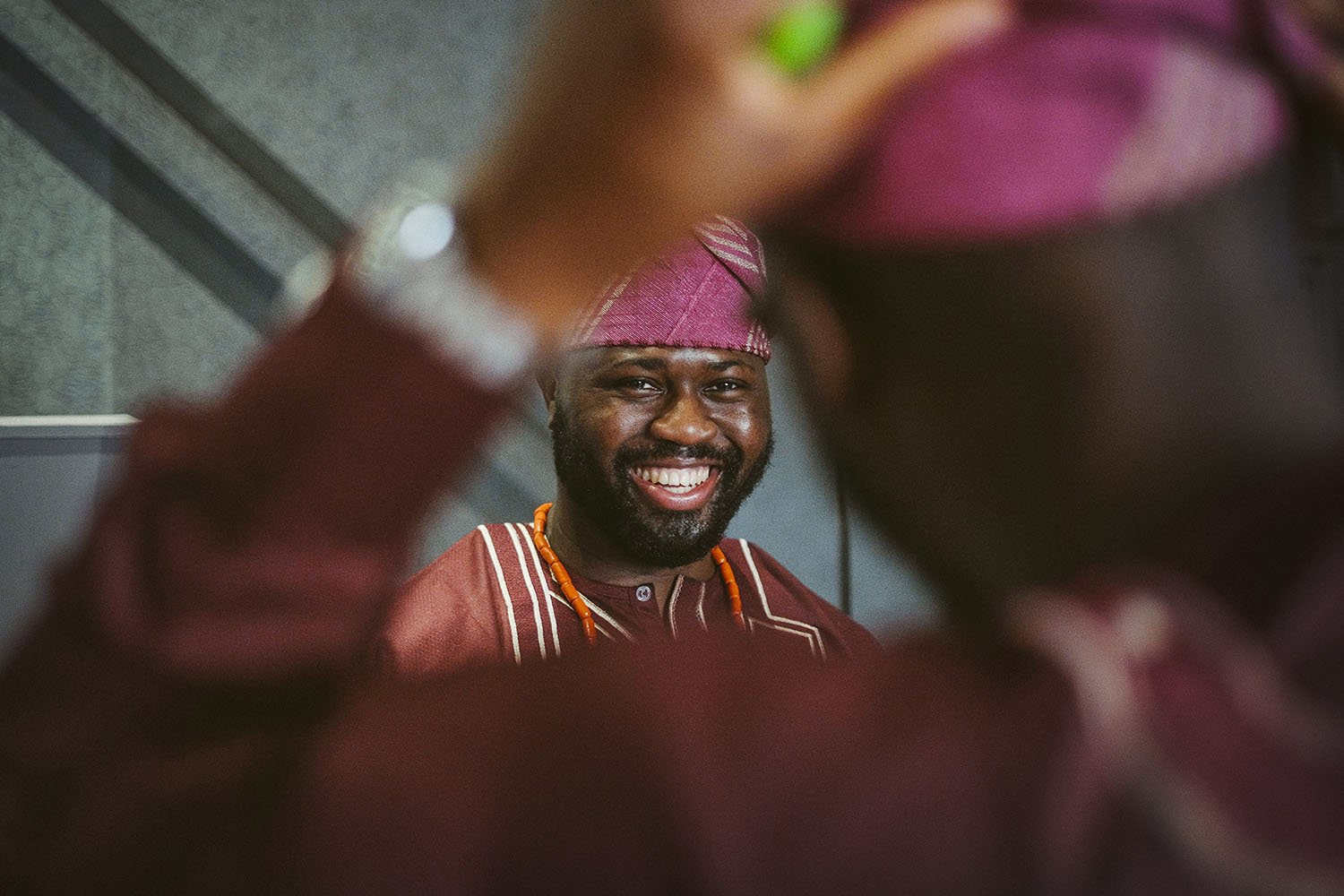 Newcastle Civic Centre wedding: smiling man in a traditional cap and embroidered top with orange beads