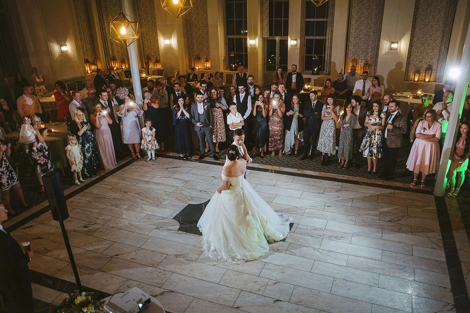 Wynyard Hall wedding: bride and groom dancing alone on a stone floor as guests circle around them.