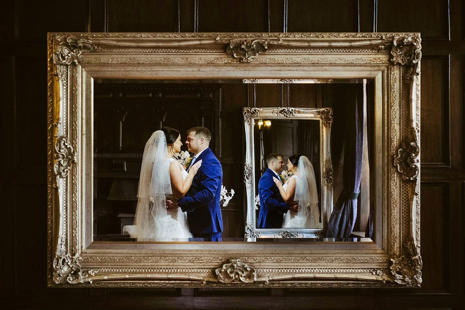 Slaley Hall wedding: bride and groom framed in a gilded picture frame with their reflection in a mirror