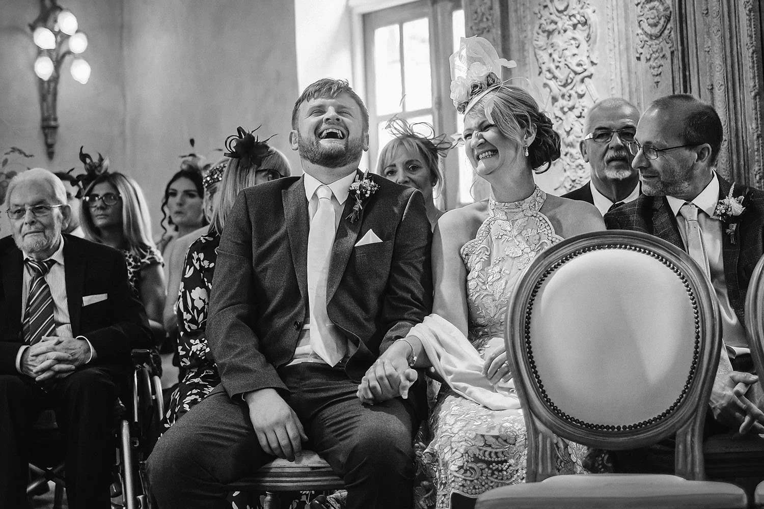 Le Petit Chateau wedding: groom laughing and holding hands with a woman beside him as guests smile around them