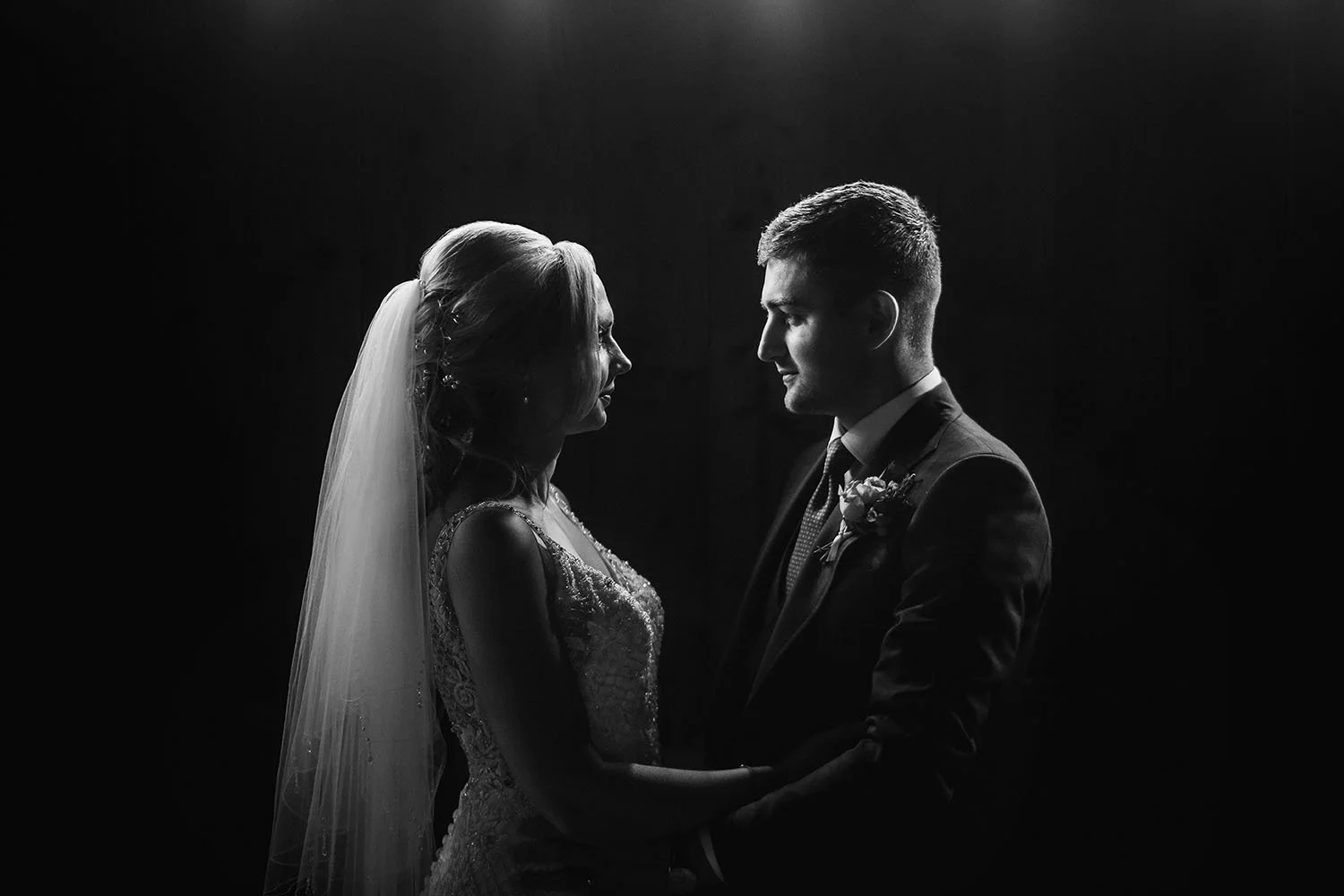 South Causey Inn wedding: bride and groom in dramatic silhouette facing each other against a dark background