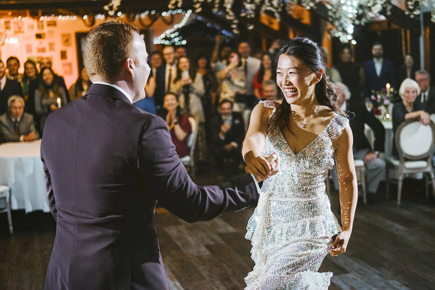 South Causey Inn wedding: bride laughing and reaching out to the groom as they begin their first dance in front