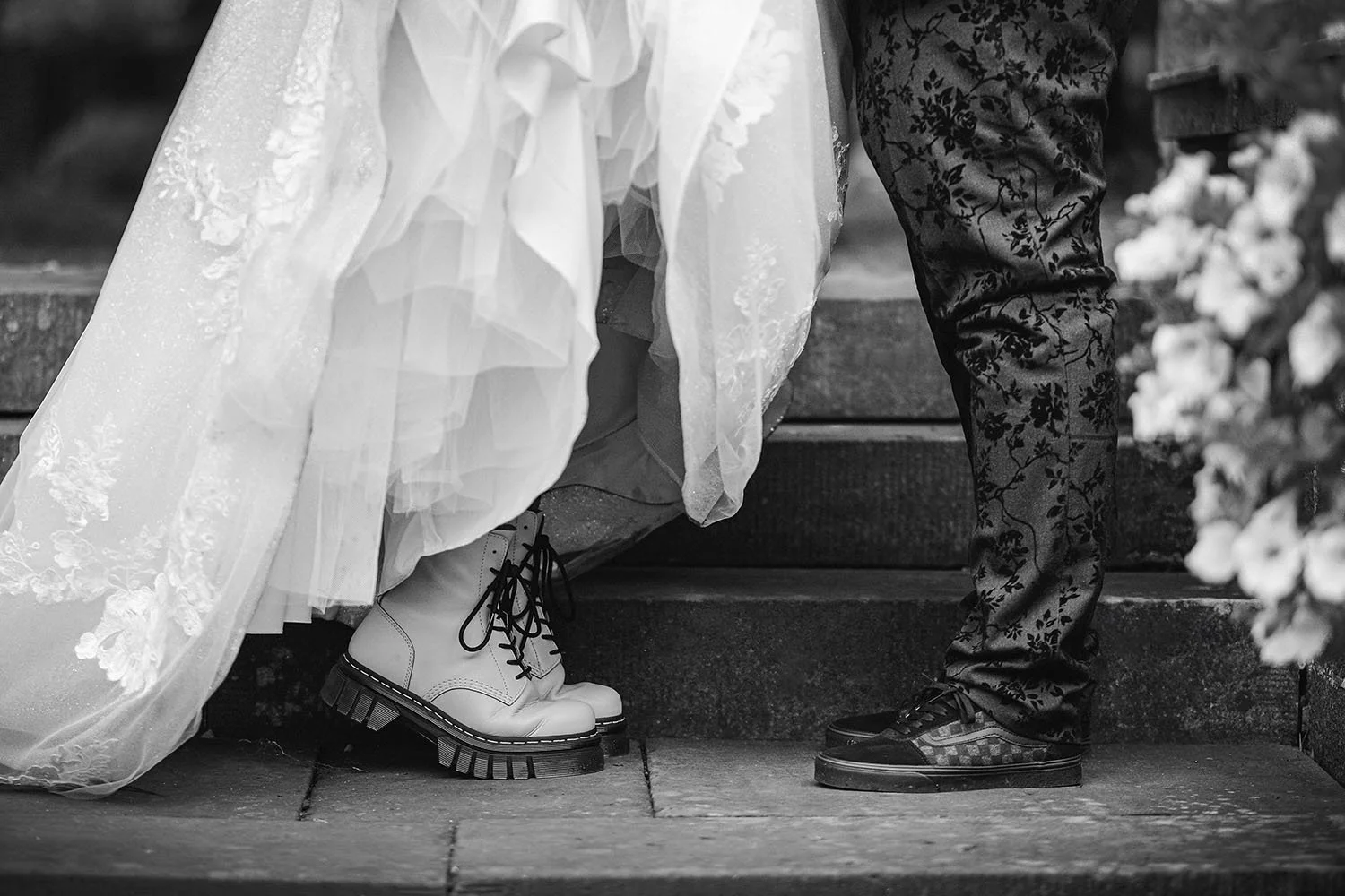Beamish Hall wedding: bride's white boots and lace dress hem beside the groom's patterned trousers and trainers on stone steps