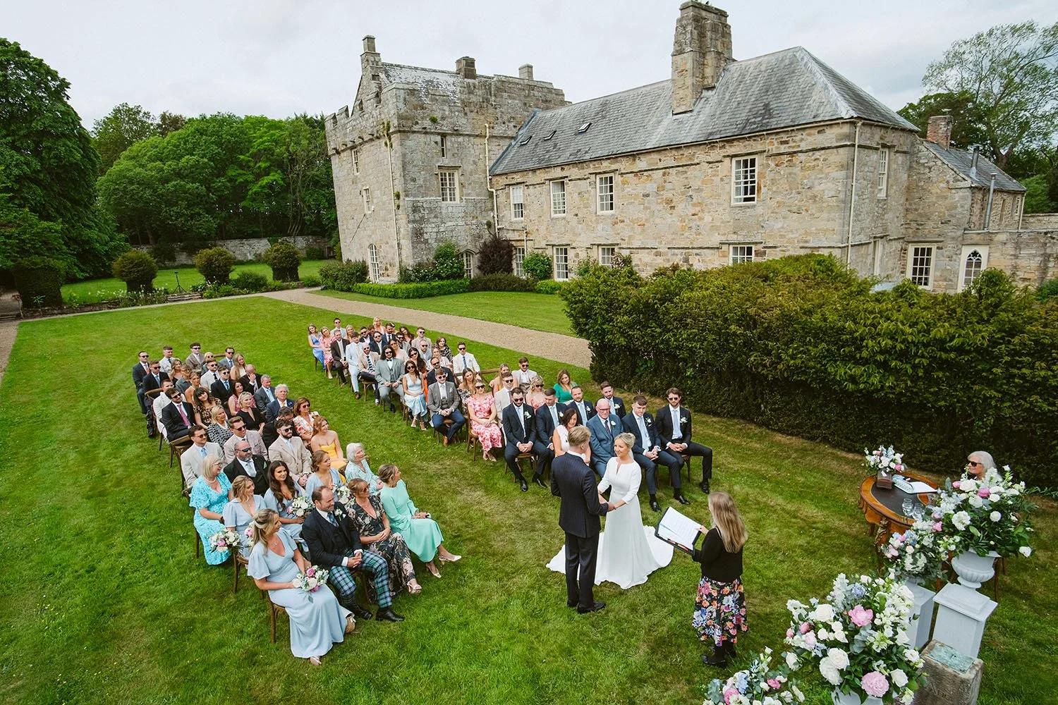 Shortflatt Tower wedding: outdoor wedding ceremony seen from above on a lawn in front of a stone manor house