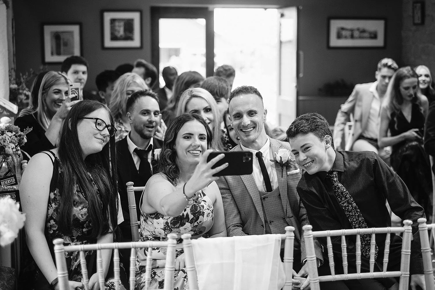 The Parlour at Blagdon wedding: wedding guests laughing and taking a selfie from their seats before the ceremony