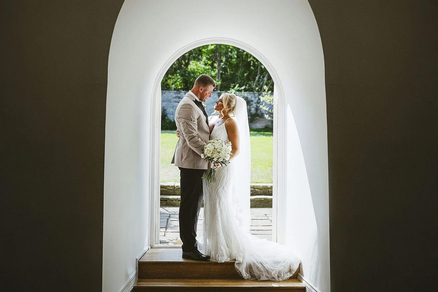 Shortflatt Tower wedding: bride and groom embracing in a white arched doorway looking out to a garden