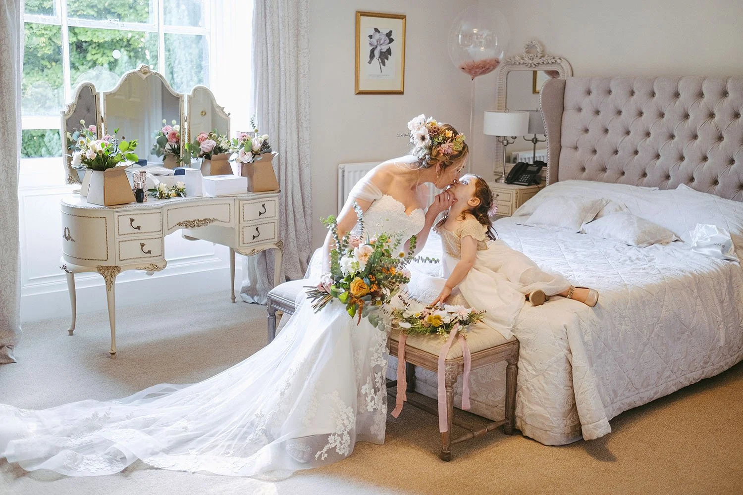 Shotton Grange wedding: bride kissing the flower girl's forehead in the flower-filled bridal suite.