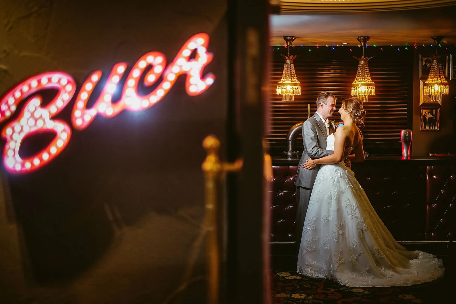 Bride and groom embracing at a pub bar behind a glowing neon sign