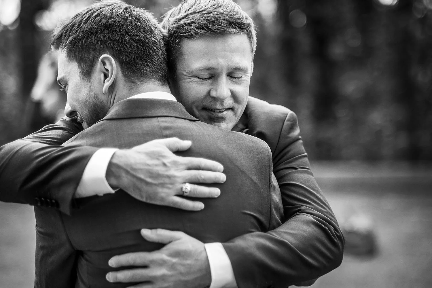 Durham Registry Office wedding: groom sharing an emotional hug with a relative, in black and white.