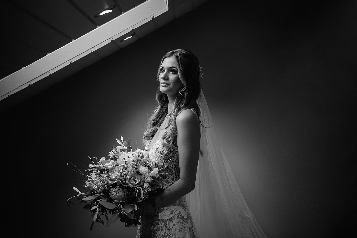 Yorkshire Wedding Barn wedding: bride holding her bouquet in a dramatic low-key light, black and white portrait
