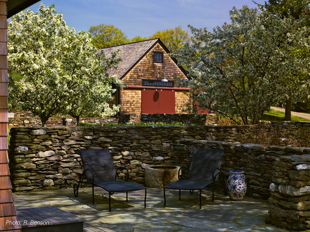 The architecture of this home, a contemporary interpretation of a classic farm complex, reflects the history of the site while looking to the future. The landscape responds to this by using local stone, a simple plant palette, and the remnants of old structures in the landscape composition. The future is celebrated by technology; photovoltaic cells powering the house and barn are placed in a field to appear as sculptural elements in the larger landscape. The project received a 2008 BSA Honor Award for Design.