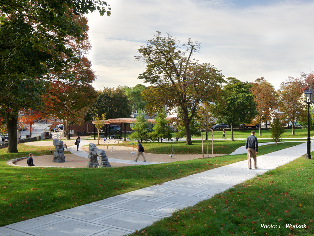 CBA's design for this neighborhood “commons” strikes a balance between refurbishing an historic greenspace and providing new activities. The site's defining diagonal walkways are joined by a meandering path connecting several new play features, selected to add a sculptural element to the site rather than the first impression being one of a playground. The many significant trees and historic stone wall around the park were protected. Paired fieldstone walls terrace the slope on both sides of the upper half of the main path, adding a dynamic element and providing more seating. Near the main entrance, a stepped wood and metal trellis shades groups of benches. The flattest area remains as open lawn for informal games. 