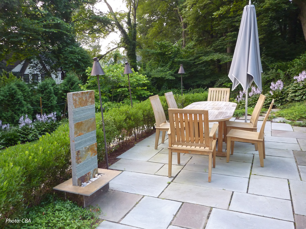 As detailed in the 2010 article "Hillside Havens" in Backyard Solutions Magazine, CBA turned what had been a neglected, overgrown hillside into unique, usable spaces. Graceful, curving stone walls tie three terraced spaces together, creating a unified design. The patio on the central terrace is the perfect spot for outdoor dining. Stairs and stepping stones connect the areas and provide an informal border for the plantings. At the bottom of the slope, an open, level lawn completes the design.