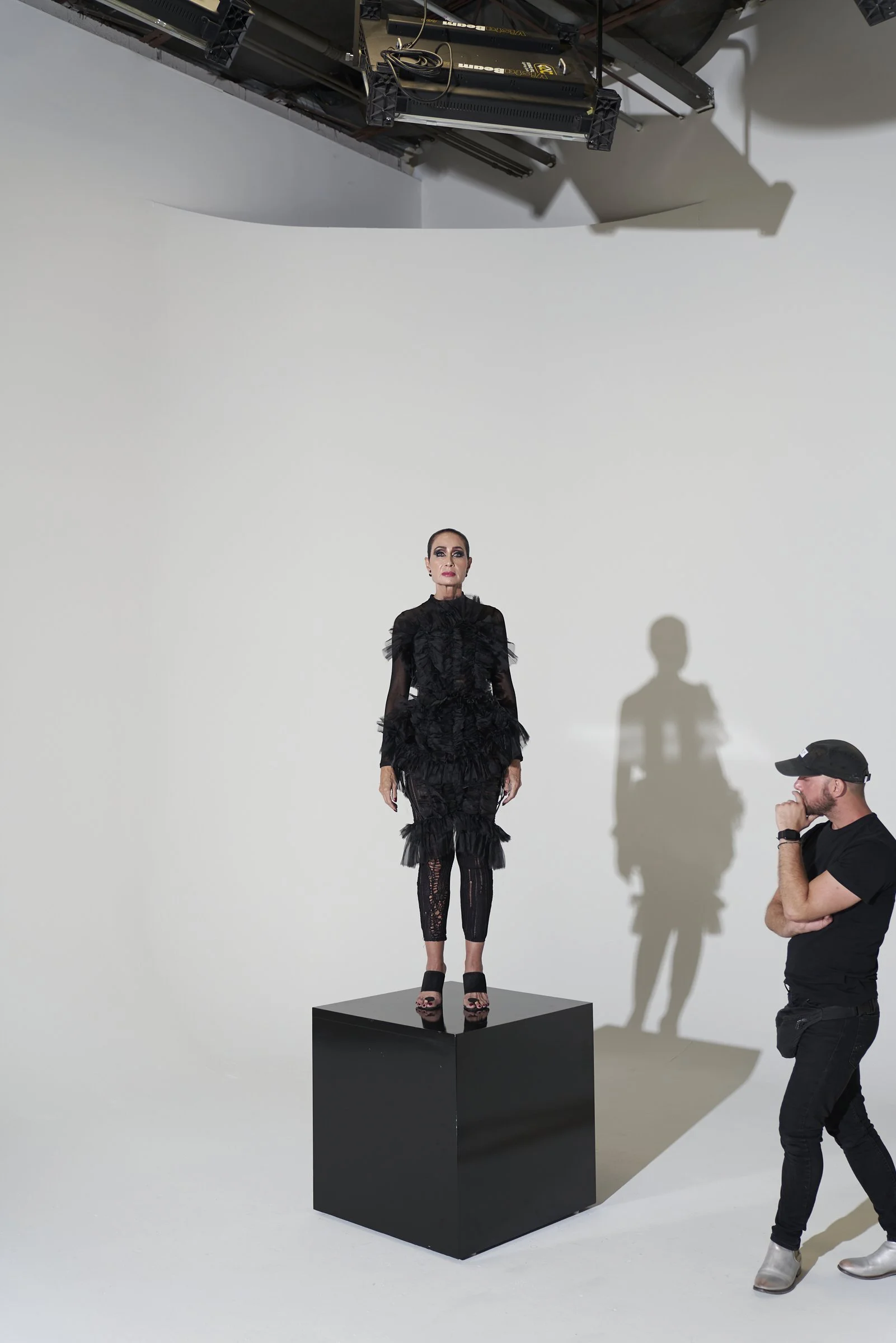 Michael Drummond studies his model Chris, who stands on a black plinth wearing a black tulle and lace piece, during the Being Played brochure shoot