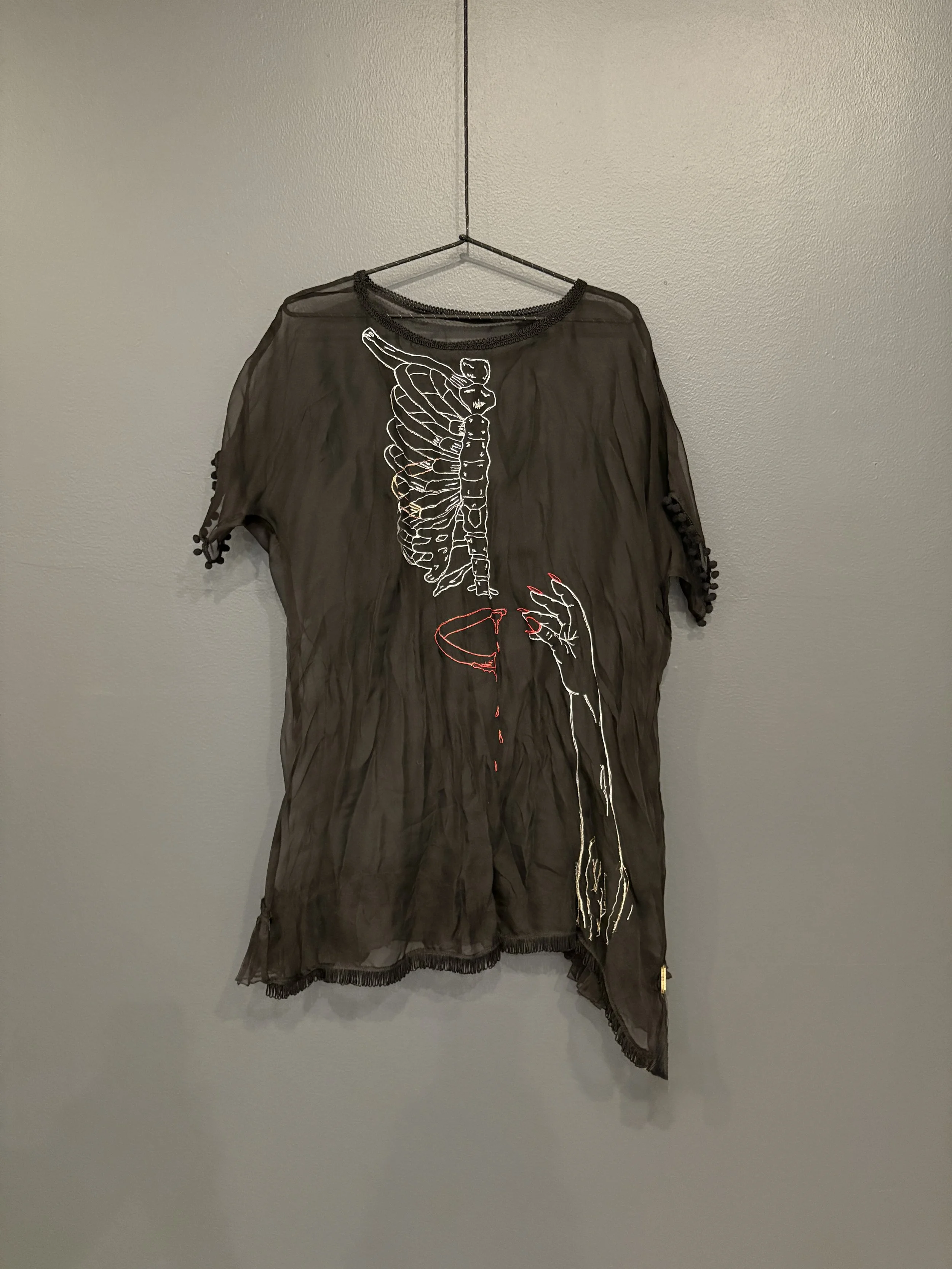 silk chiffon dress with a ribcage and hand embroidered on black silk hanging from a hanger