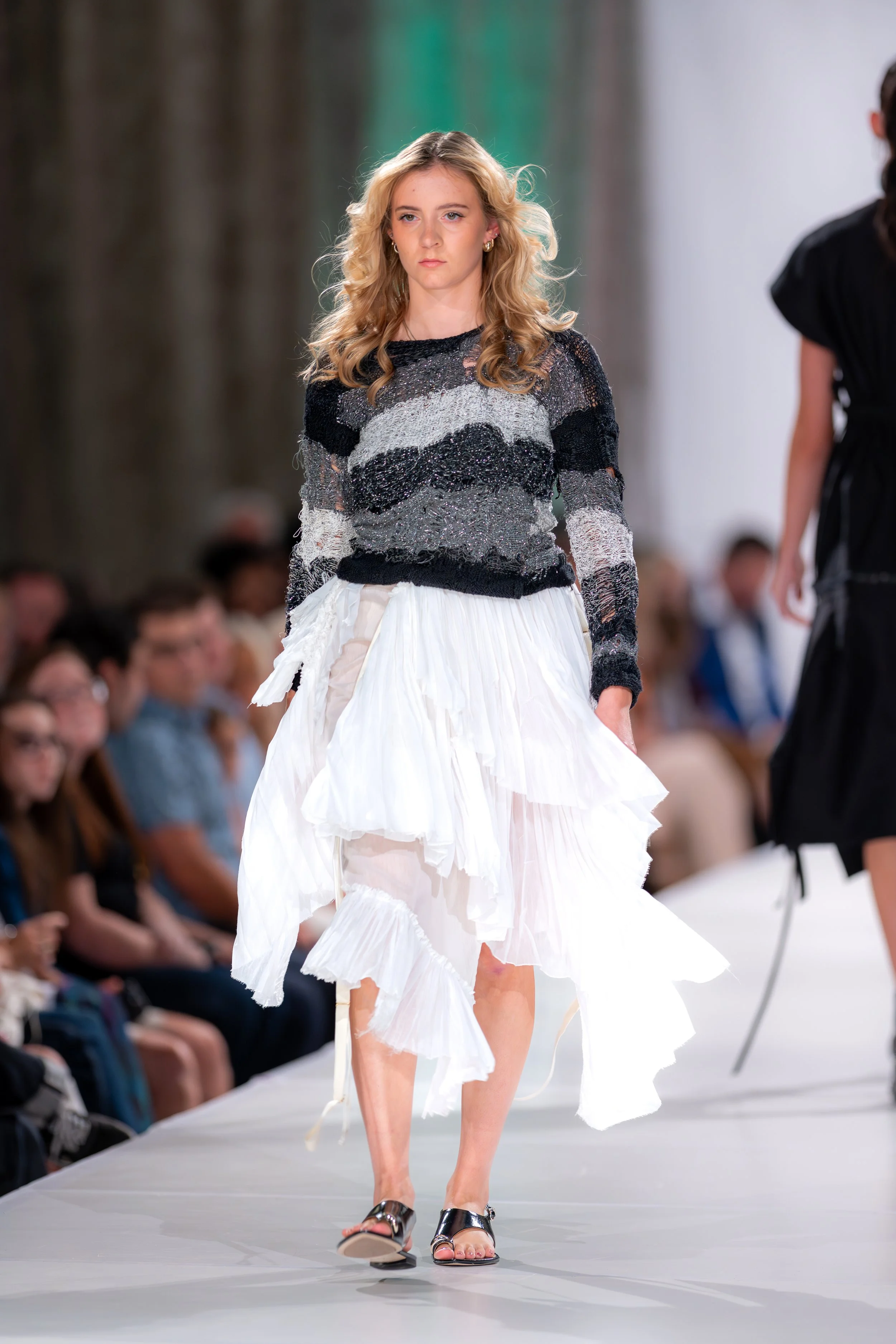 Hand-knit sweater in cotton, wool, and Lurex with sculptural slubs and mixed-media texture in grey, black, and silver. Deadstock wrap skirt featuring layered ruffles and an elastic waistband in white.

Kansas City Fashion Week
Fall/Winter 2025