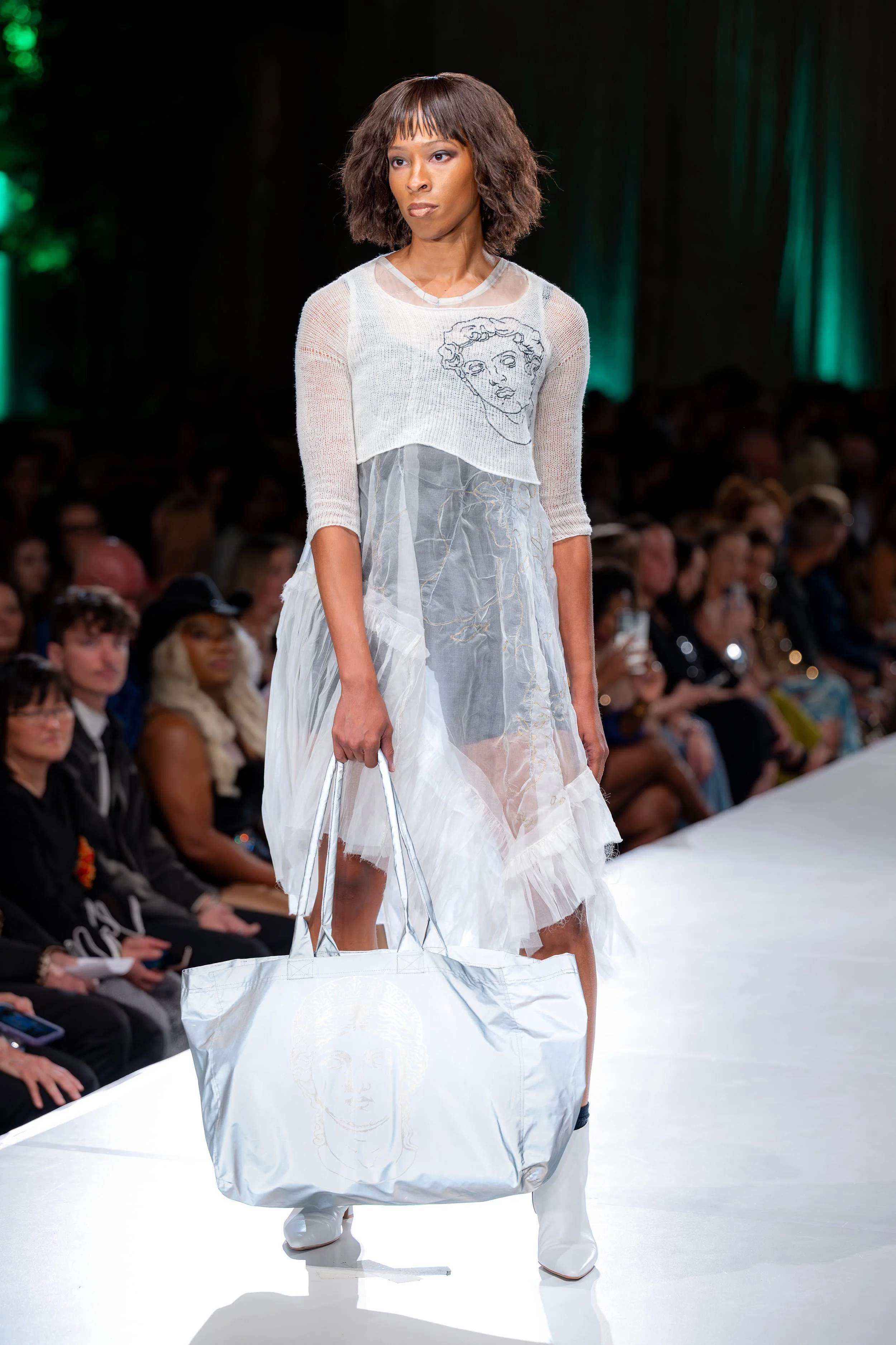 Deadstock hand knit mohair white pullover, hand guided machine embroidery, silk organza dress with hand guided machine embroidery, and 3M tote bag with interior pocket and laser etched image of a woman crying.

Kansas City Fashion Week F/W 2025