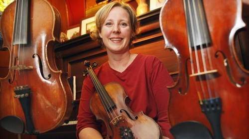 JASON HUNTER-WATERTOWN DAILY TIMES Violin/fiddle instructor and performer Gretchen Koehler, the latest inductee into the New York State Fiddlers' Hall of Fame, sits on a piano bench with her beloved stringed instruments in her home in Potsdam. 