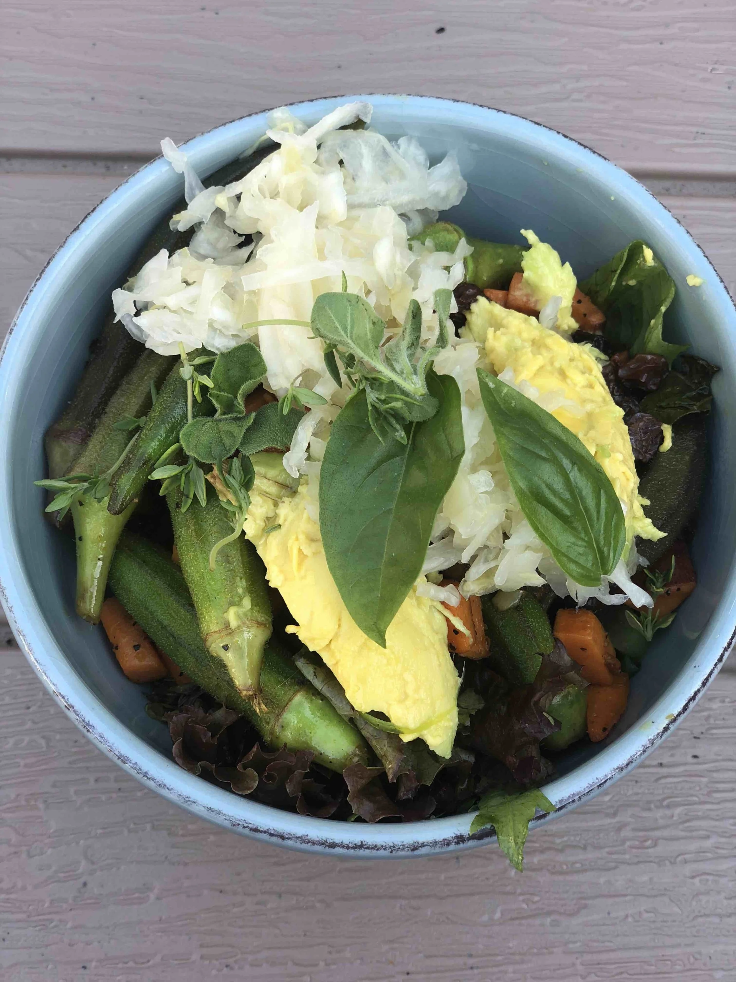 Okra Bowl with sauerkraut, avocado, sweet potato and farmers market lettuce topped with garden herbs