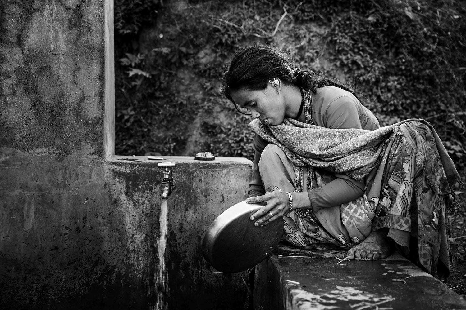 A young woman washes the dishes after lunch on a water supply tap. These taps are part of RVWRMP's support program.