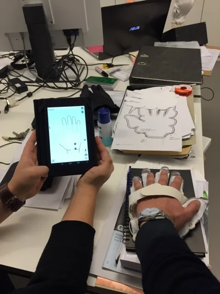 Rechts der 4. Prototyp des Handschuhs, auf der App kann man mitlesen, welche Sensoren beim Empfang vibrieren. 