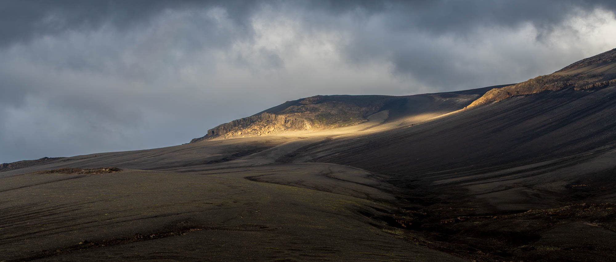 Sunlit Slope Under a Dark Storm Cloud.jpg