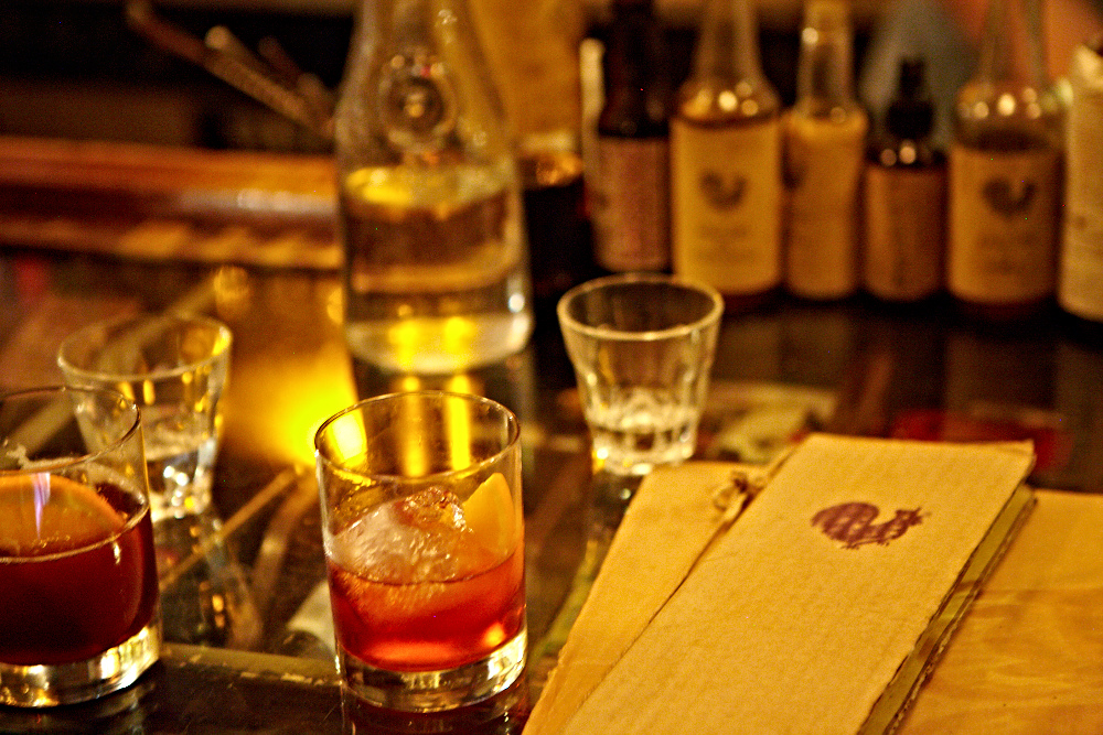 Our classic negroni on our bar, with pharmacy related items under the glass.