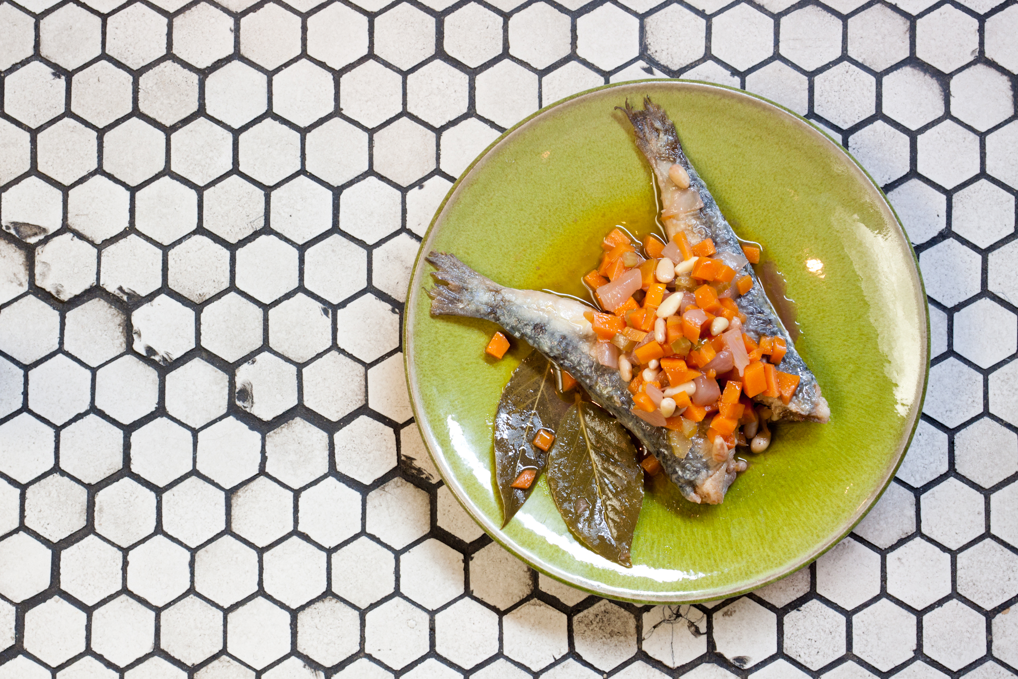 A plate of venetian style sardines on a small hexagonal tiled surface