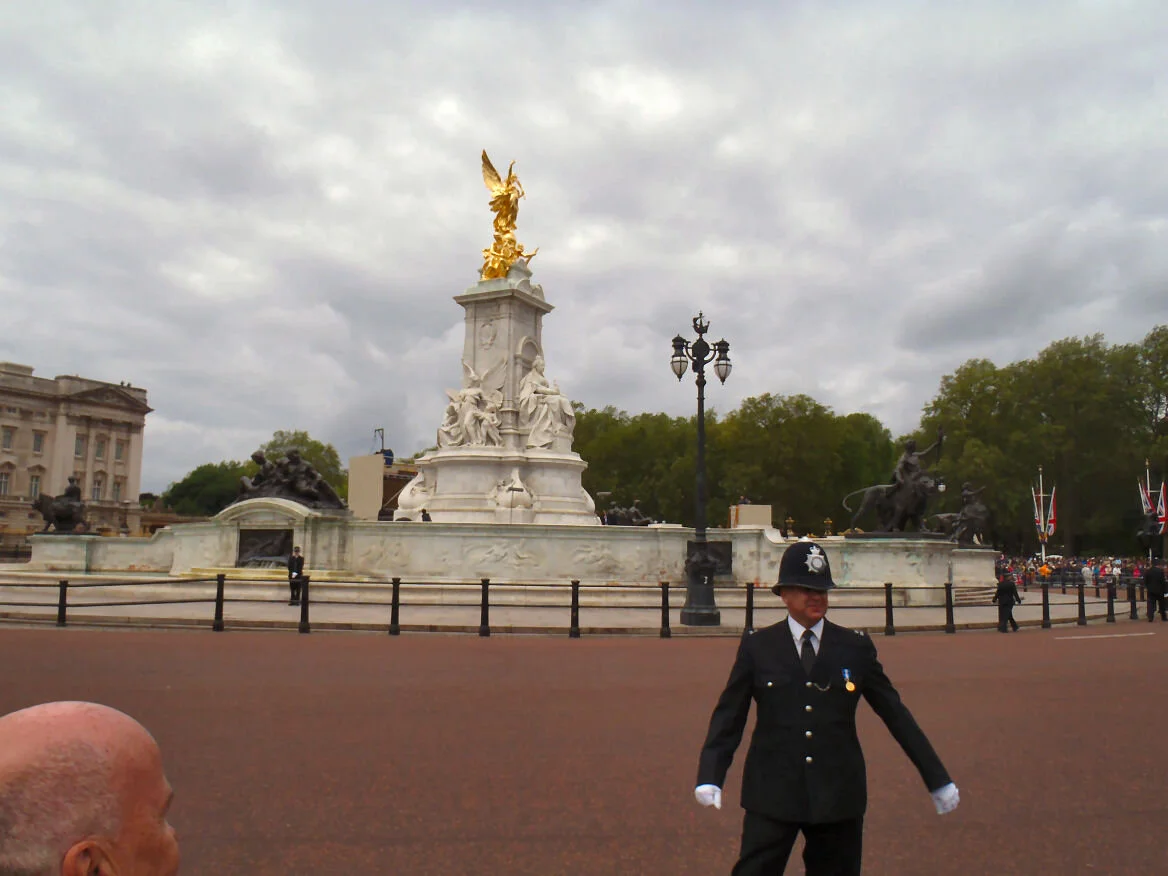 Standing looking at Buckingham Palace next to the railing