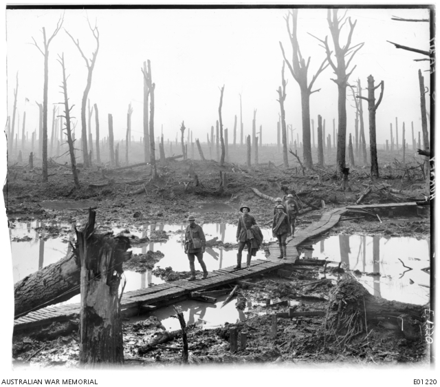 Australian soldiers on duckboard track over mud and water (Australia War Memorial)