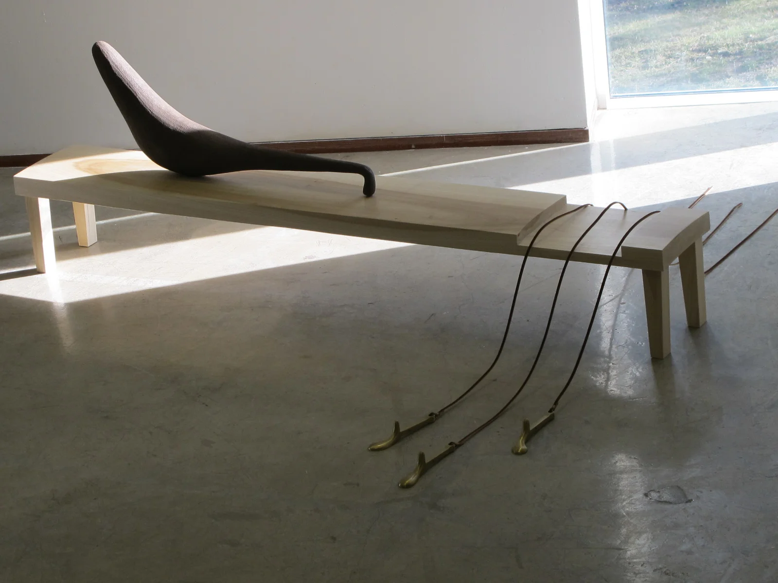 Sostenuto, 2010. Stoneware 38"L x 20"H x 6"W. poplar bench 72" x 10" x 10". Leather straps 60" L. Brass forms 7" x 2.5"