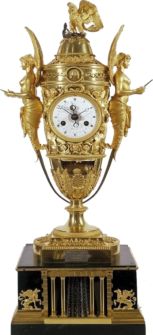 "Napoleon's timepiece in the shape of an amphora (1806), equipped with an eight-day movement, it displays the hours, minutes and date. It has a mechanism displaying the moon phases inside the day hand, by means of a tiny ivory ball. Napoleon and Josephine are crowned Emperor and Empress as soon as the music box is activated. To achieve this, an ingenious mechanism physically places the imperial crown on their heads. Bronzier Pierre-Phillipe Thomire, movement Louis Moinet." -- Wikiwand After many adventures, the clock was displayed at the universal exposition in Paris, 1900
