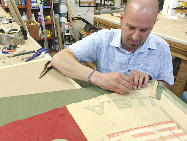 Our framer/owner, Eric, hand stitched the 61.75" by 25.5" pennant to a hand-wrapped sea-foam green fabric mat. 