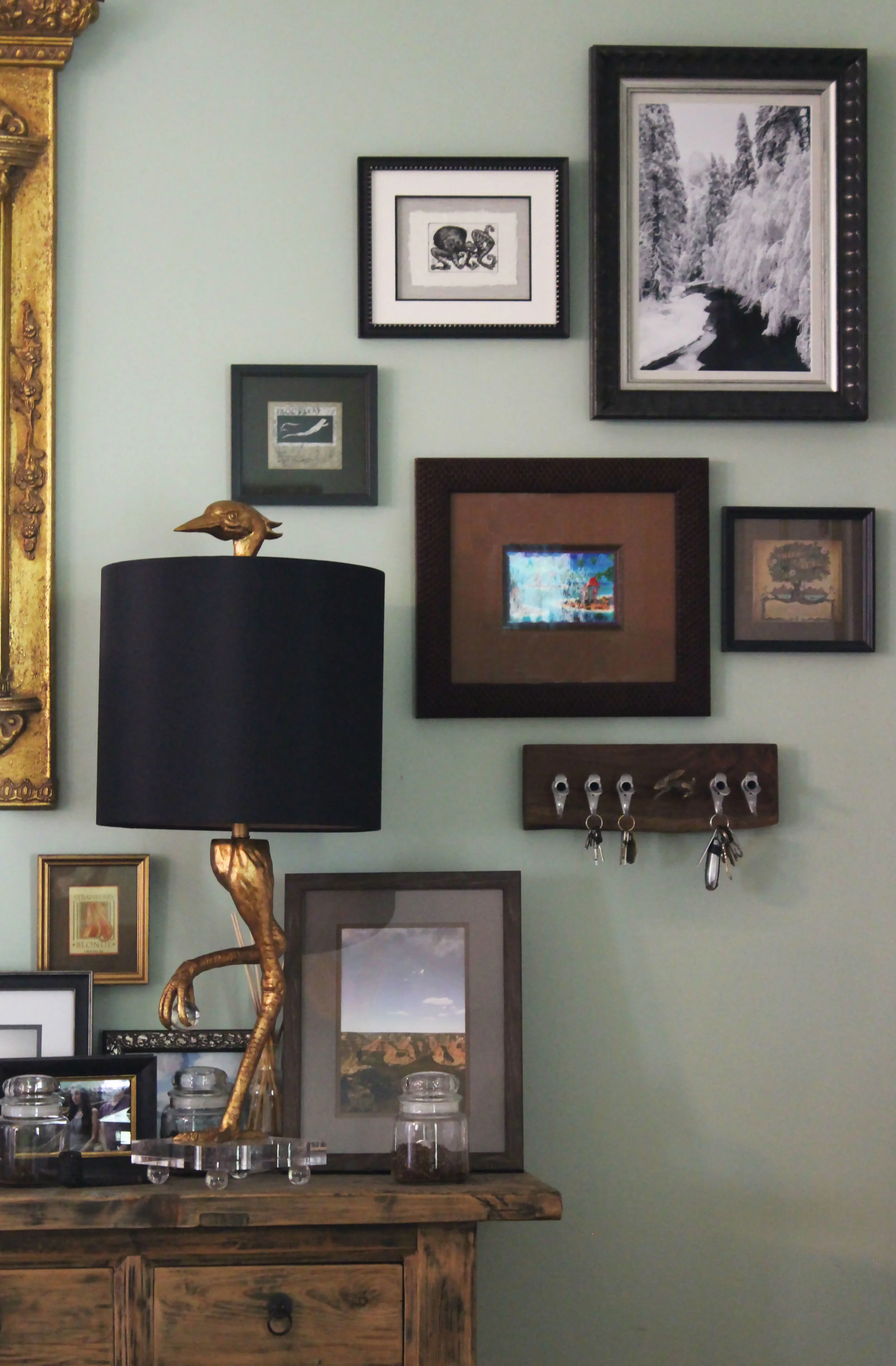 This entryway grouping incorporates an ibis bird lamp and maple spout key rack. Working around three-dimensional pieces can add visual interest to an otherwise flat viewing space. 