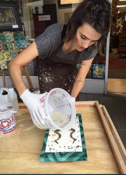 Kathryn Silvera coats a piece of artwork with resin during Open Studio Tours last year.