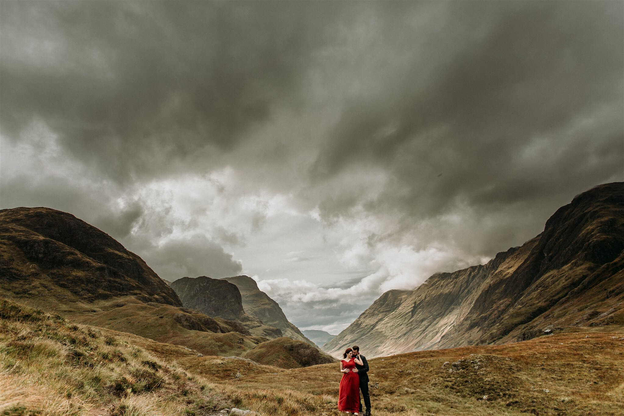 Glen Coe Scotland elopement adventure session. Bride in red dress with her groom in a field Scottish Highlands | Adventure elopement photographer