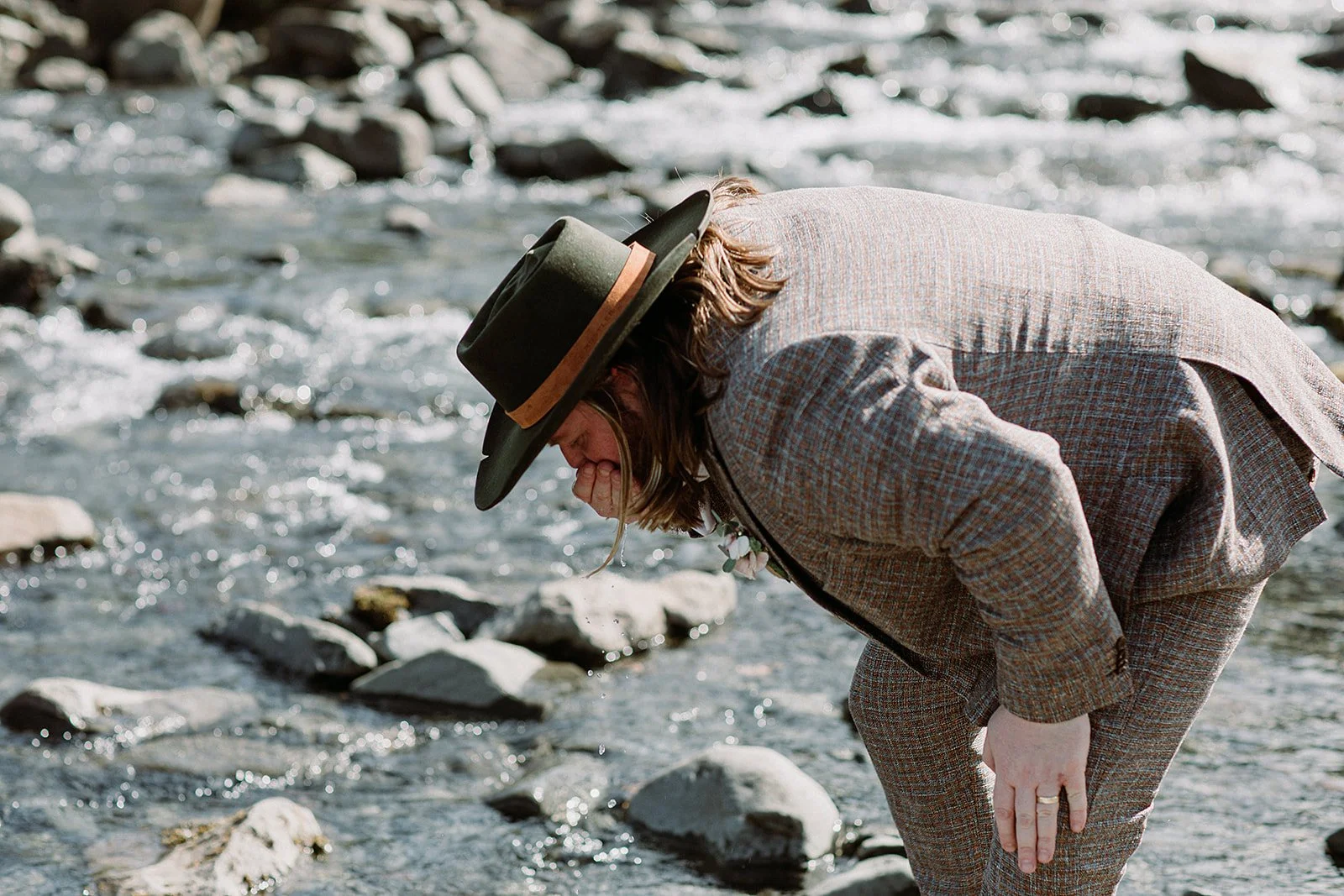 private Iceland elopement in black wedding dress groom drinking from river