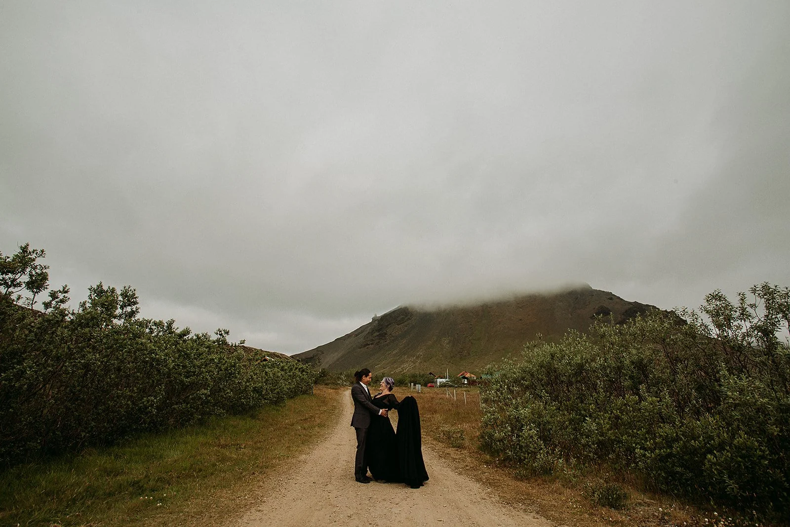Alternative Iceland elopement couple wearing black wedding dress and purple hair — couples adventure photos