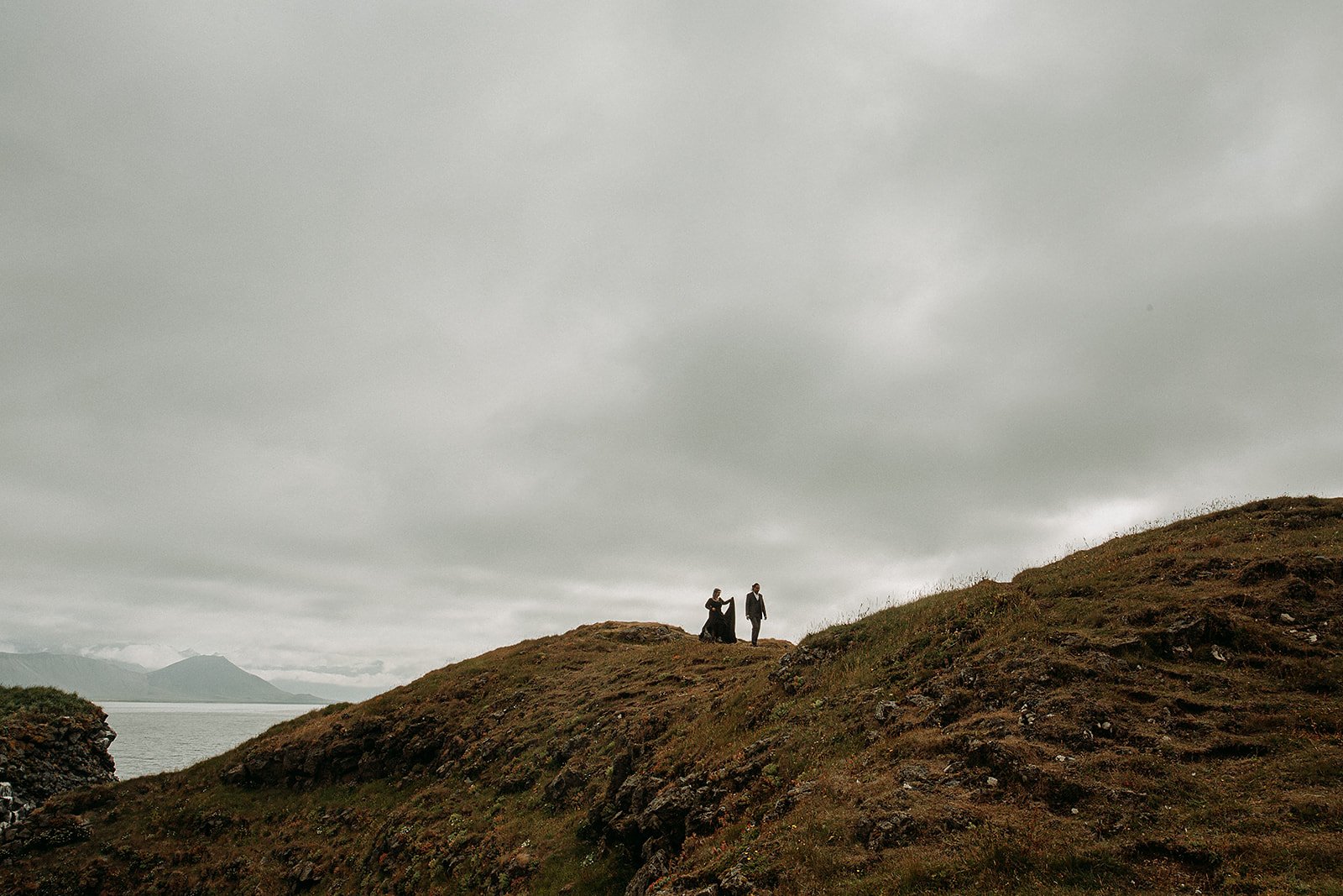 Alternative Iceland elopement couple wearing black wedding dress and purple hair — couple portraits sea cliffs Snæfellsnes
