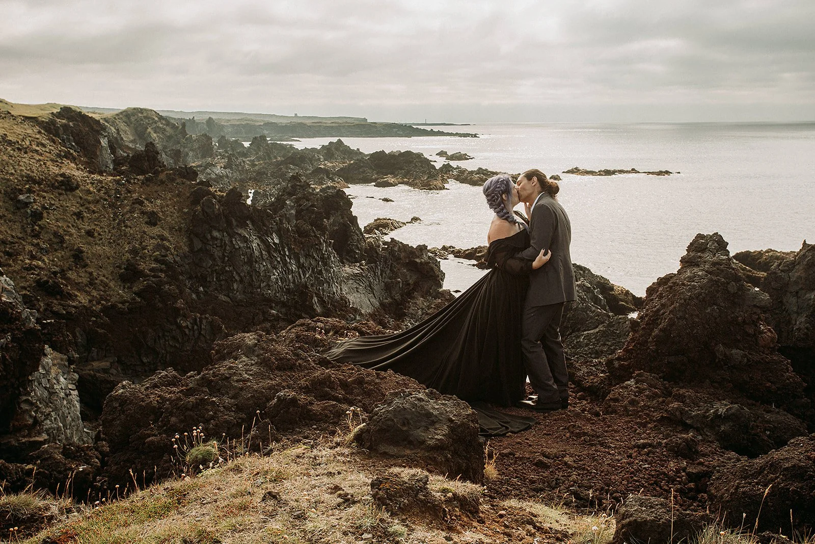 Alternative Iceland elopement couple wearing black wedding dress and purple hair — couple saying vows wedding ceremony