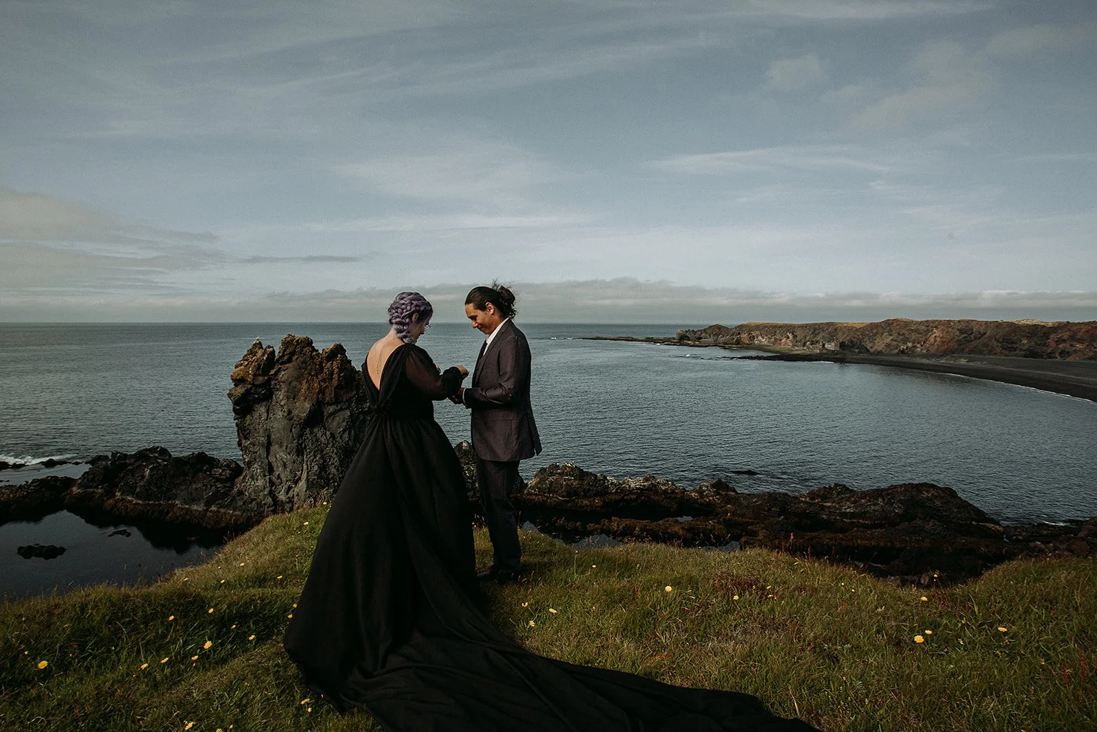 Alternative Iceland elopement couple wearing black wedding dress and purple hair — couple portraits at black sand beach