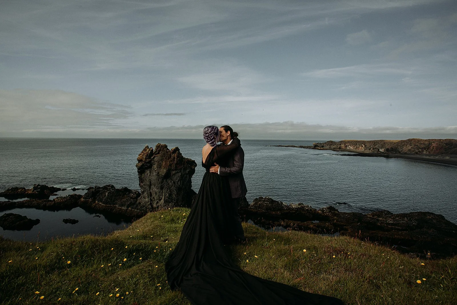 Alternative Iceland elopement couple wearing black wedding dress and purple hair — couple portraits at black sand beach
