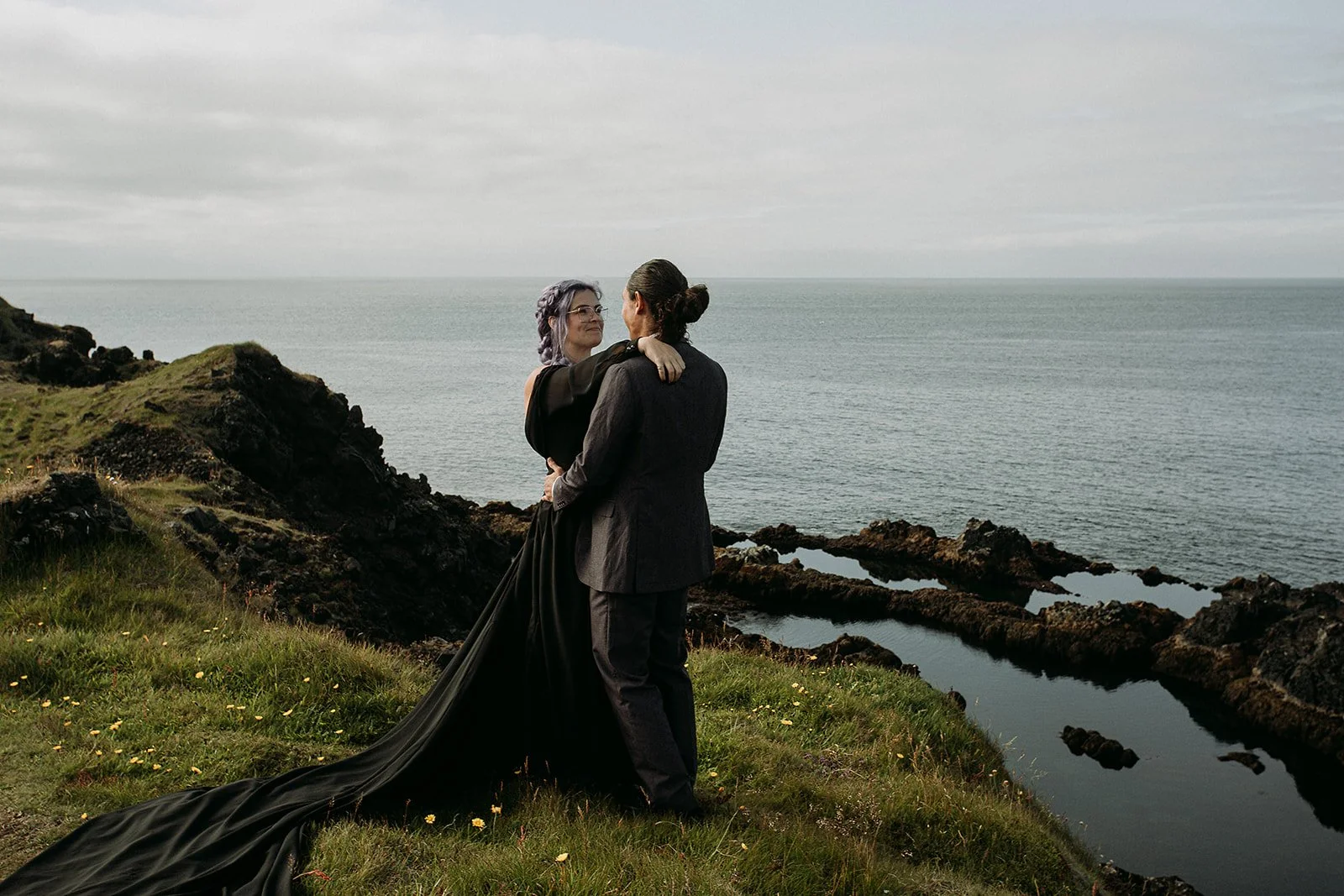 Alternative Iceland elopement couple wearing black wedding dress and purple hair — couple portraits at black sand beach