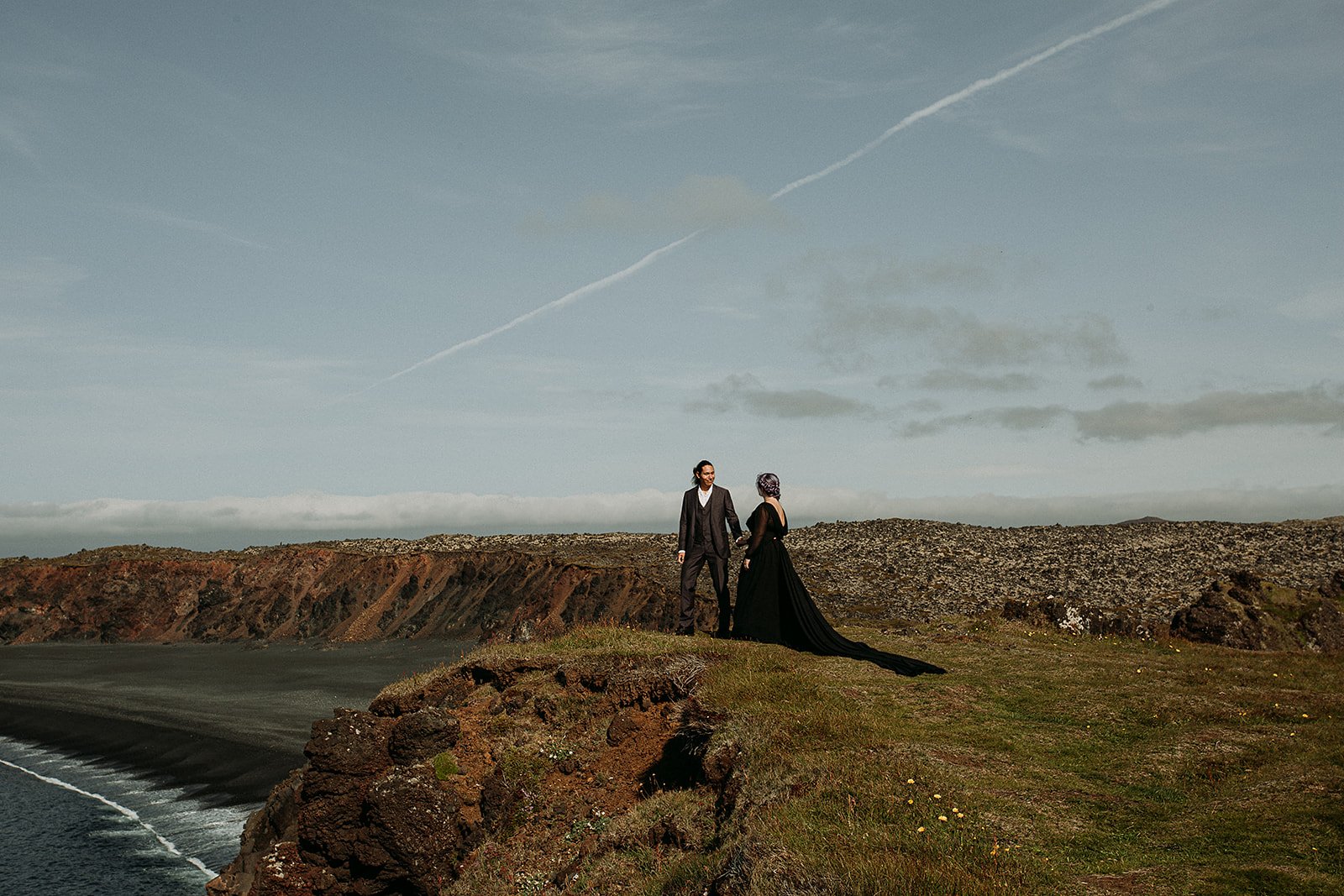 Alternative Iceland elopement couple wearing black wedding dress and purple hair — couple portraits at black sand beach