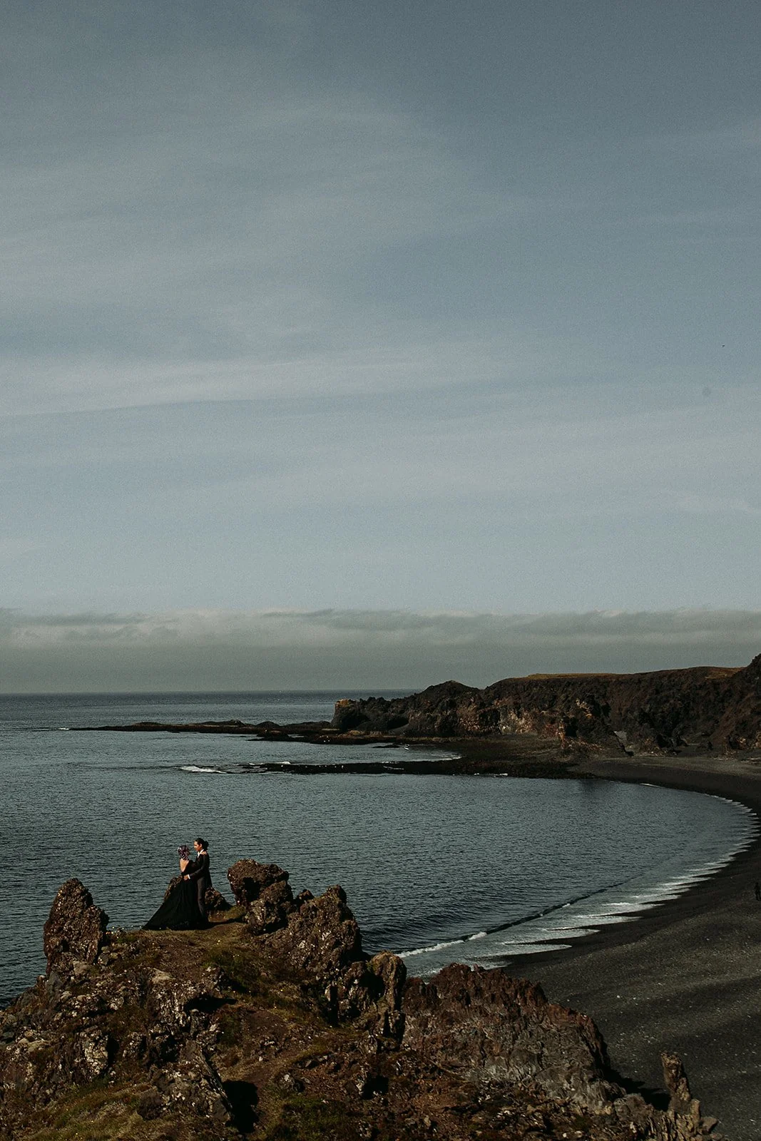 Alternative Iceland elopement couple wearing black wedding dress and purple hair — couple portraits at black sand beach