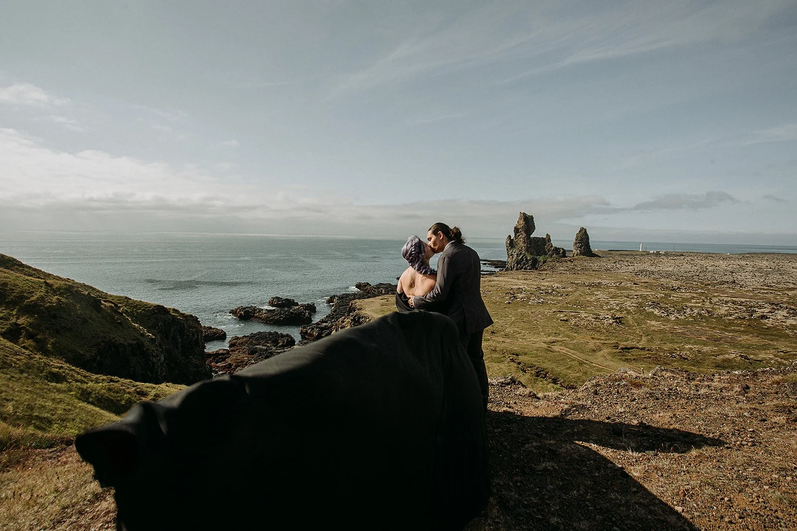 Alternative Iceland elopement couple wearing black wedding dress and purple hair — couple portraits at black sand beach