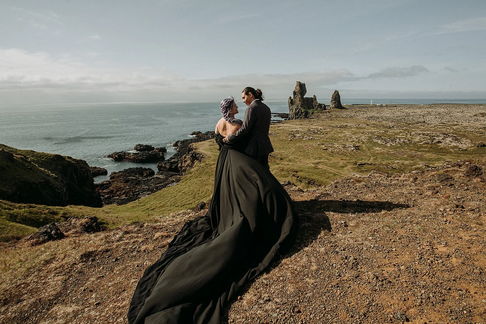 Alternative Iceland elopement couple wearing black wedding dress and purple hair — couple portraits at black sand beach